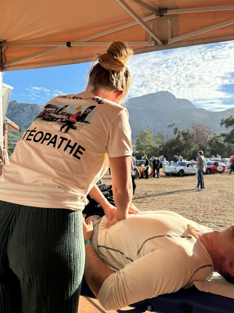 Laurina en séance sous le chapiteau du Tour de Corse Historique, voitures de rallye et montagnes en arrière-plan